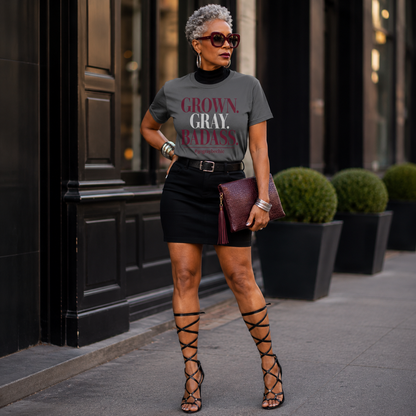 Woman wearing a gray t-shirt with text, black skirt, and high-heeled shoes standing on a city street.